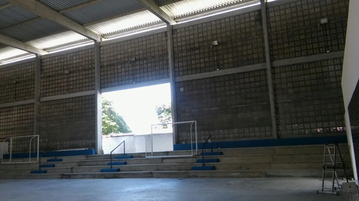 Ginásio esportivo com arquibancadas e quadra em concreto